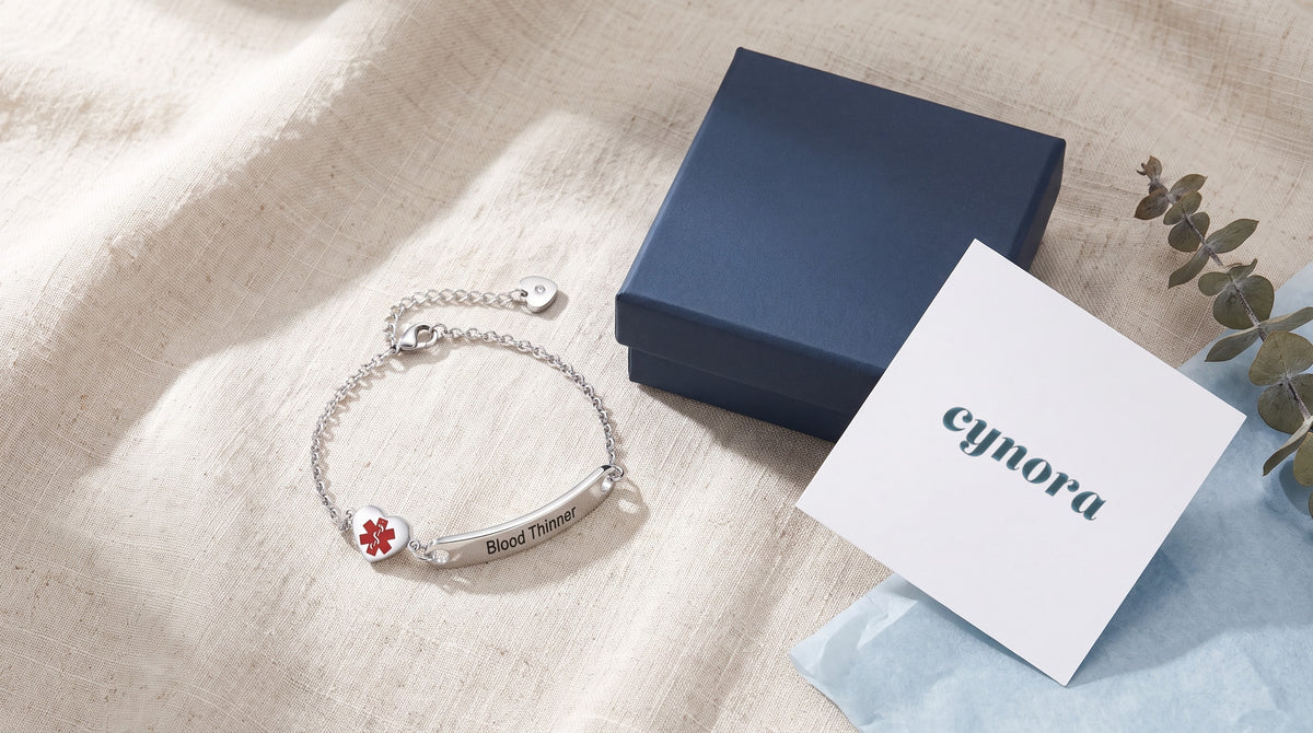 Cynora medical ID bracelet with navy gift box and Cynora card on linen